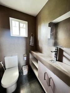 a bathroom with a toilet and a sink and a window at Serenity Home near Ayala Malls Serin in Tagaytay