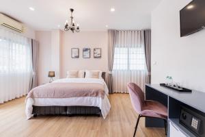 曼谷Casa Luna的一间卧室，配有一张床和一张带电视的书桌
