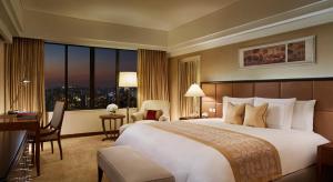 a hotel room with a large bed and a desk at The Portman Ritz-Carlton Shanghai in Shanghai