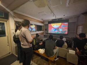a group of people sitting in a room watching a movie at TenTen Guesthouse in Asakusa in Tokyo