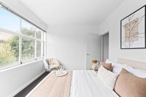 a white bedroom with a bed and a window at The Bluewater Nest in Melbourne