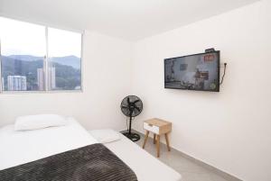 Habitación blanca con 2 camas y TV de pantalla plana. en Apartamento Medellin-sabaneta a cuadra del metro, en Sabaneta