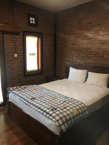 een groot bed in een kamer met een bakstenen muur bij Tamansari Homestay in Sawan
