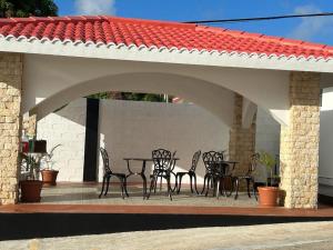 un patio con mesa y sillas bajo un techo en Mariana Suites, en San Roque