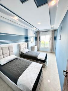 two beds in a room with blue walls at Abraj Dubai Larache in Larache