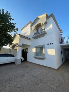 een wit huis met een auto ervoor geparkeerd bij Loft A cerca zona dorada in Mexicali