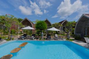 een zwembad in een resort met stoelen en parasols bij The Mel Huts in Nusa Penida