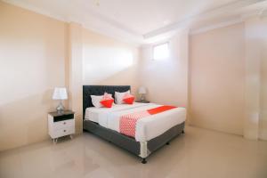 本哲的住宿－OYO 1667 Edotel Smkn 1 Pacet Syariah，一间卧室配有一张带红色枕头的大床