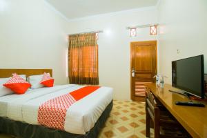 a hotel room with a bed and a flat screen tv at OYO 1667 Edotel Smkn 1 Pacet Syariah in Puncak
