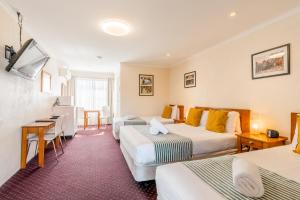 a hotel room with two beds and a desk at The Henry Parkes Tenterfield in Tenterfield