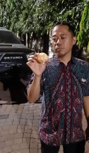 Un uomo sta mangiando una ciambella per strada di SENAYAN SUITES a Giacarta