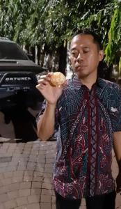 a man is eating a donut on a street at SENAYAN SUITES in Jakarta