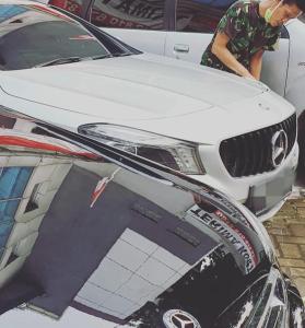 a man is standing next to a white car at SENAYAN SUITES in Jakarta