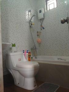 a bathroom with a toilet and a bath tub at ERN Travellers Inn House in Mindoro in Kabalwa