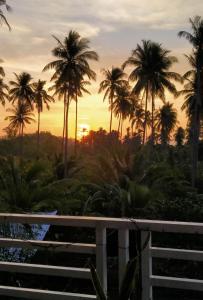 a sunset view from the balcony of a resort with palm trees at Peaceful and Romantic Country Home in Kabalwa