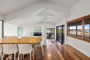 comedor y sala de estar con mesa de madera y sillas en Emerald on the Beach House, en Emerald Beach