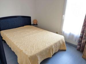 um quarto com uma cama com um edredão amarelo e uma janela em Maison Marseillan-Plage, 4 pièces, 6 personnes - FR-1-387-196 em Marseillan