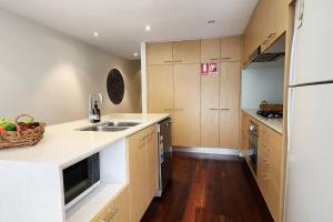 eine Küche mit Holzschränken, einer Spüle und einer Theke in der Unterkunft Stylish parkside retreat in Sydney