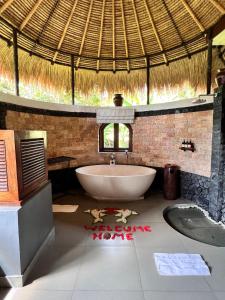 a bathroom with a tub and a straw roof at Subak Tabola Villa in Sidemen