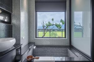 a bathroom with a tub with a window and a sink at Jiaoxi 320 B&B in Jiaoxi