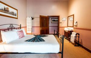a bedroom with a bed and a bathroom with a sink at The Henry Parkes Tenterfield in Tenterfield