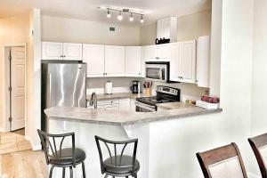 a kitchen with white cabinets and a stainless steel refrigerator at Downtown Kelowna 2 Bdrm 2 Bath Waterfront Condo in Kelowna