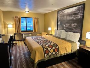 a hotel room with a large bed and a desk at Super 8 by Wyndham Eau Claire WI in Eau Claire