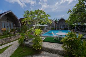 um resort com piscina, mesa e cadeiras em The Mel Huts em Nusa Penida