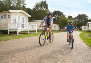 un homme et un enfant à bord d'un vélo sur une route dans l'établissement Spacious Caravan - Thorpe Park Cleethorpes, à Humberston