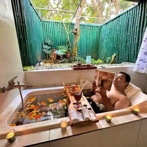 Un uomo sdraiato in una vasca da bagno con una foto di Shanti Wellness Sanctuary a Lemery