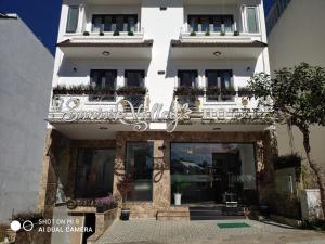 Sunrise Valley Dalat Hotel في دالات: مبنى أبيض مع شرفة عليها زهور