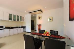 una cocina con mesa con sillas y un bol de fruta en Rawai Grand House -SHA Plus, en Rawai Beach