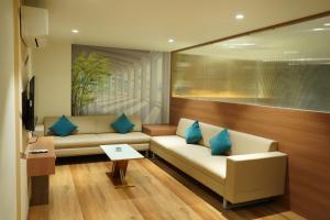 sala de estar con 2 sofás blancos y almohadas azules en HOTEL OM INN, en Gandhinagar