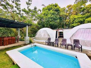 a swimming pool with two domes and tents at Shanti Wellness Sanctuary in Lemery