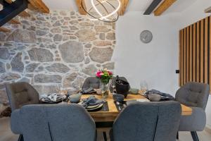 a dining room table with chairs and a stone wall at Villa Green Garden in Hreljin