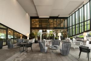 Courtyard by Marriott Vilnius City Center في فيلنيوس: مطعم يوجد به كراسي وطاولات في مبنى