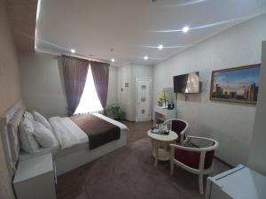 a hotel room with a bed and a desk and a table at The Royal Hotel in Samarkand