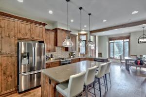 a kitchen with a stainless steel refrigerator and wooden cabinets at Village Walk #21 By Bear Country in Sun Peaks