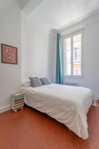 Un dormitorio con una gran cama blanca y una ventana en L'Atelier d'Artiste - refuge bohème et créatif, en Toulon