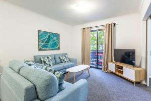 een woonkamer met een blauwe bank en een tv bij Stylish Apt In The Heart Of Perth City in Perth