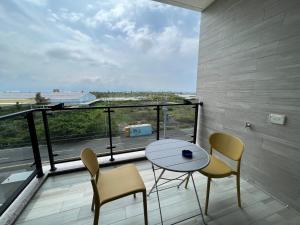 a balcony with a table and chairs and a large window at Dongjin Bay B&B in Donggang
