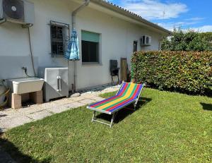 a colorful chair sitting in the grass in front of a house at Casa Licanio in Bibione