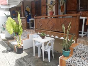 een patio met een tafel, stoelen en planten bij Sandstorm Lodge and Cafe in Puerto Galera