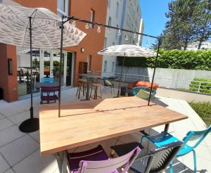 een houten tafel met stoelen en parasols op een patio bij Aparthotel Adagio Access Dijon République in Dijon