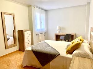 1 dormitorio con cama, escritorio y espejo en Vista a Quenxe, en Corcubión