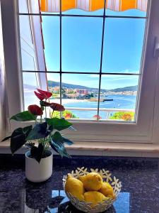 una ventana con un tazón de limones delante de un tazón de fruta en Vista a Quenxe, en Corcubión