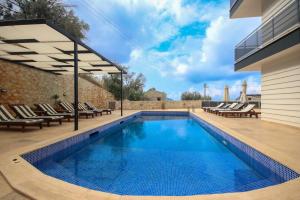 a swimming pool with lounge chairs and a house at Apollon Apartment in Kalkan