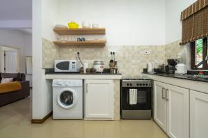 a kitchen with a washing machine and a microwave at Kanasuk Self catering Apartments in Baie Lazare Mahé
