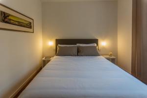 a bedroom with a large white bed with two tables at La casa del Vescovo in Imola