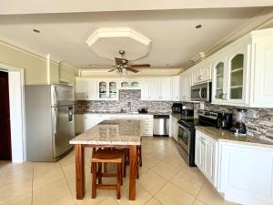 a kitchen with white cabinets and a ceiling fan at Oceanview Rancho with Two bedroom & Two baths in Coco